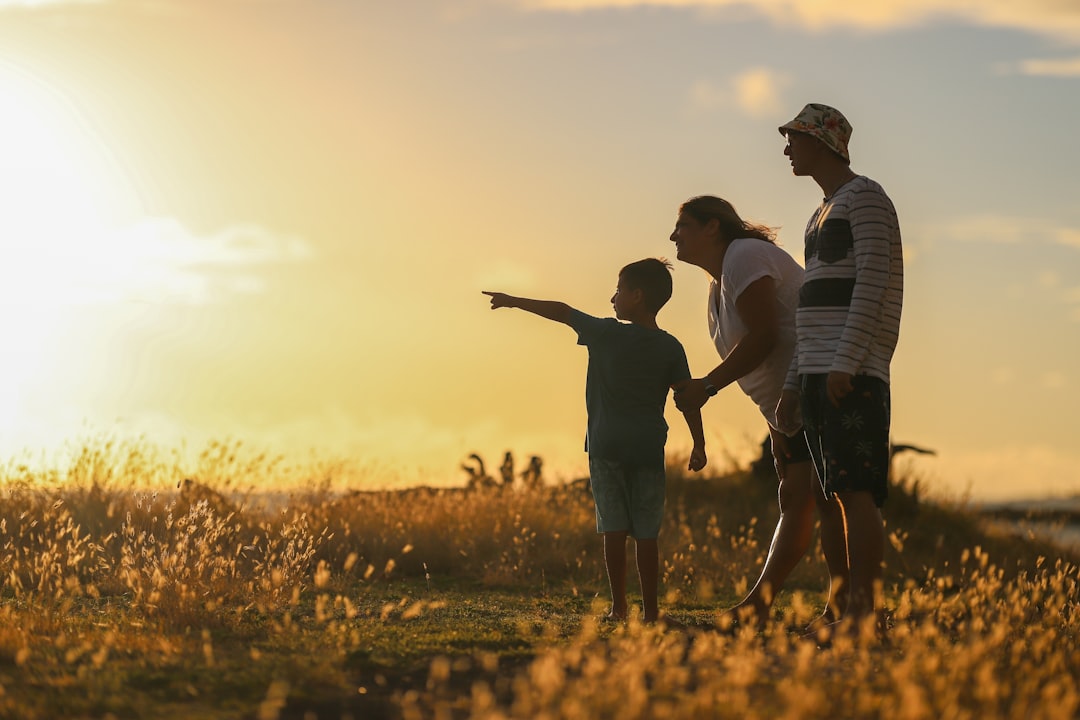 Photo by Luemen Rutkowski man and woman holding hands while walking on grass field during sunset